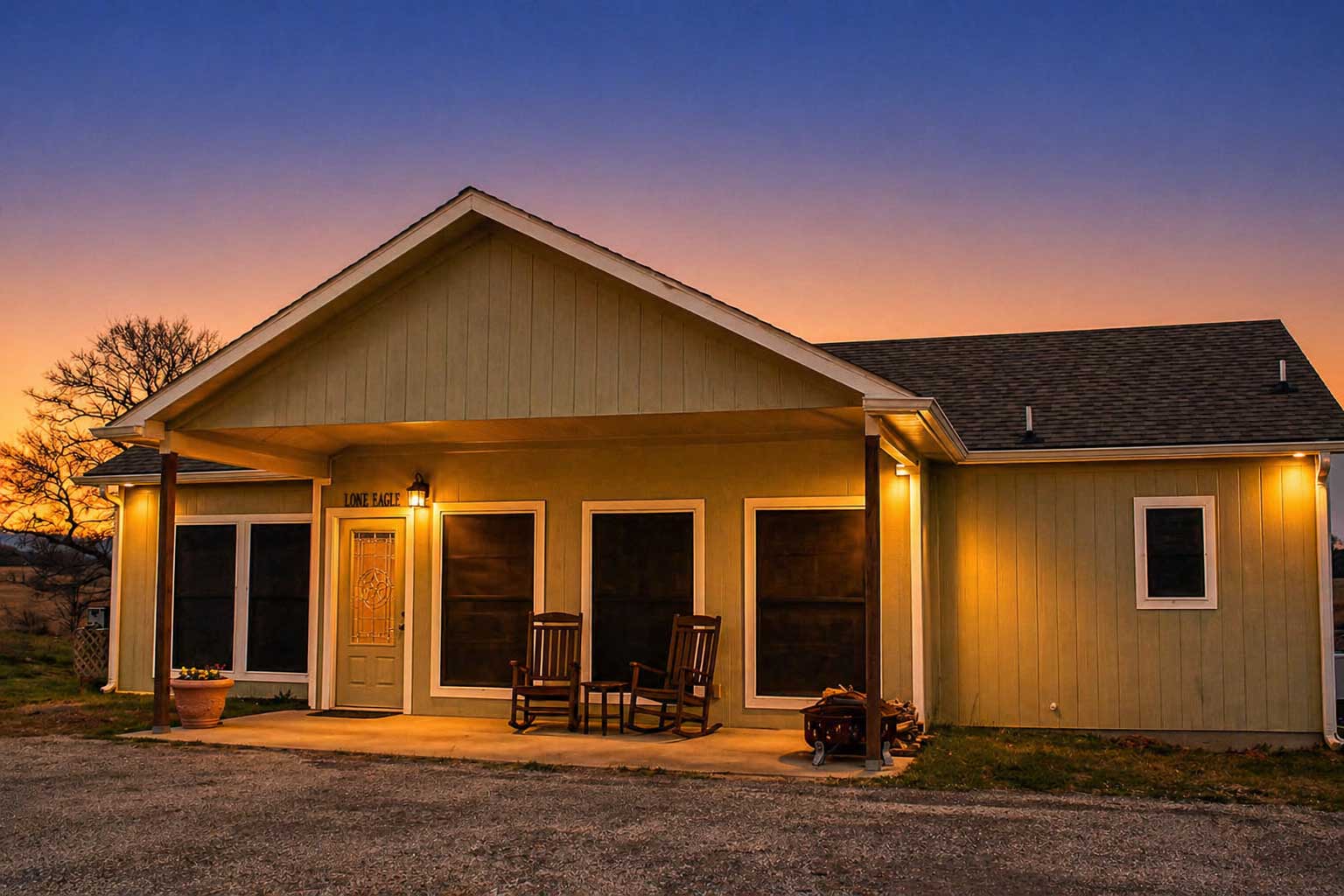 Lone Eagle cabin at Willowood Ranch with porch lights on at twilight, featuring rustic wood beams and peaceful countryside views