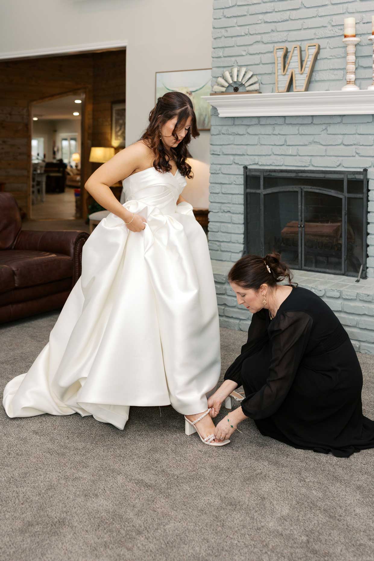 Mother helping bride put on wedding shoes during getting ready moments at Willowood Ranch wedding venue in North Texas