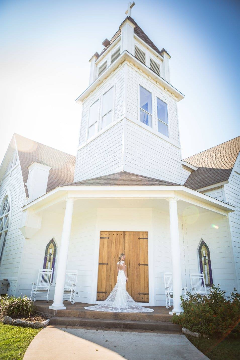 Bride standing at chapel entrance at Willowood Ranch wedding venue in Bells Texas near Dallas with white chapel and wooden doors