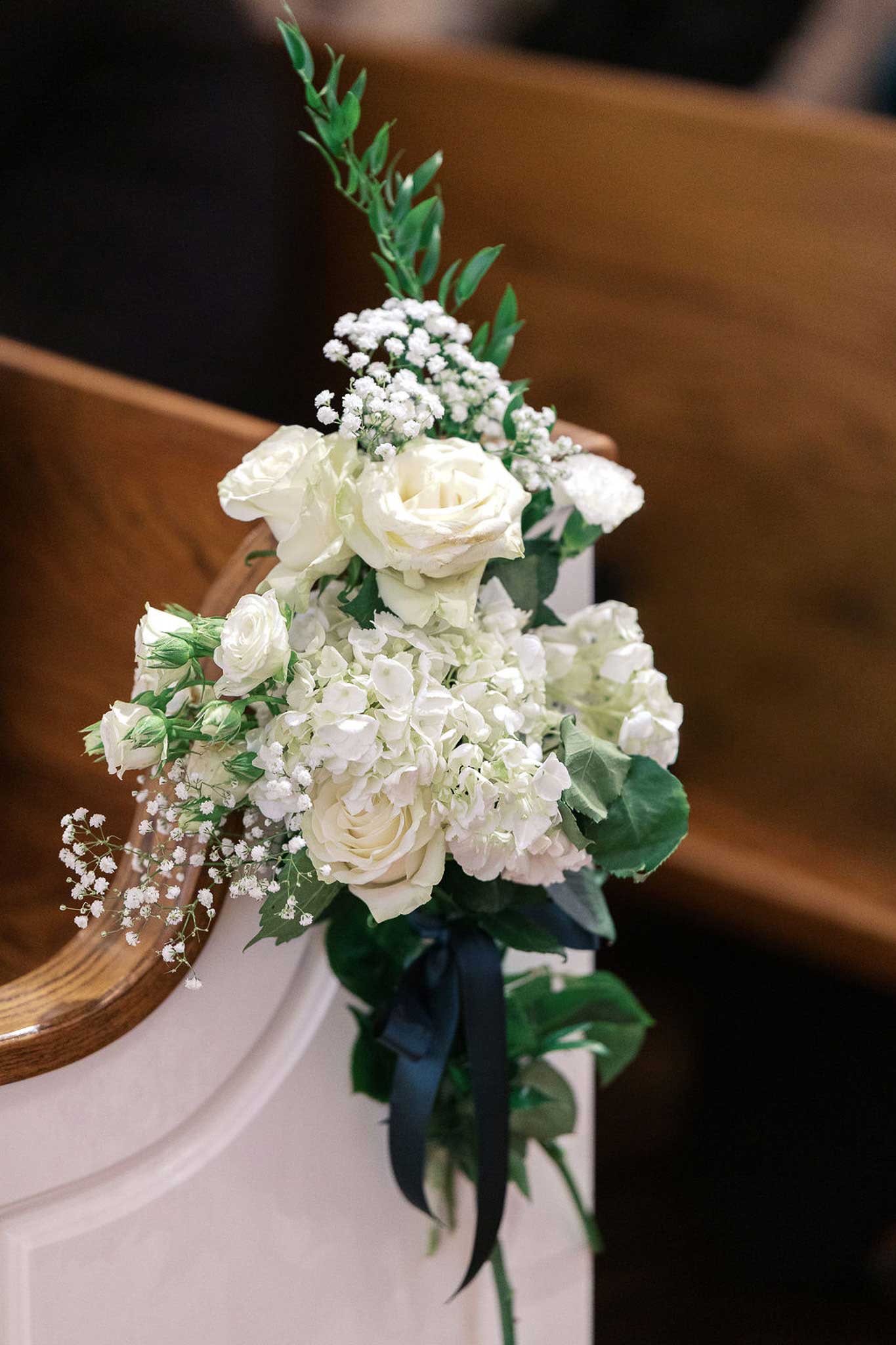 White floral arrangement on chapel pew at Willowood Ranch wedding venue in North Texas