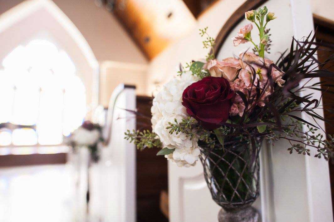 Floral arrangement on chapel pew at Willowood Ranch wedding venue in Bells Texas