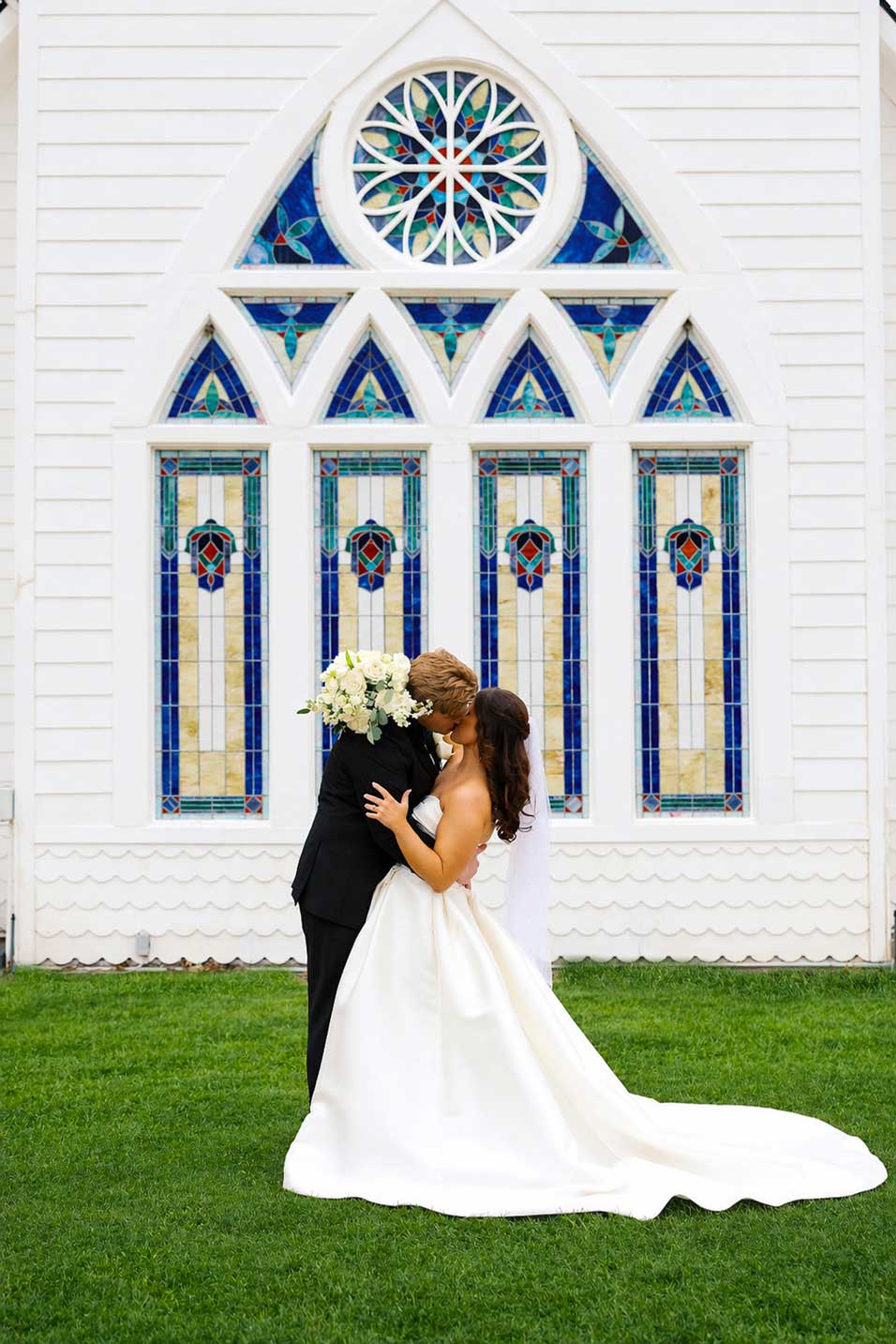 Bride and groom kissing in front of stained glass chapel at Willowood Ranch wedding venue in North Texas