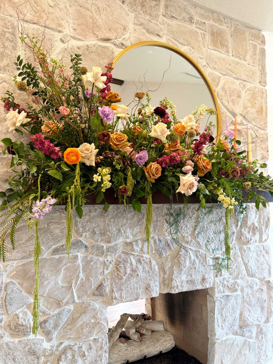Colorful wedding floral arrangement styled across a stone fireplace mantel inside Willowood Ranch event center in North Texas