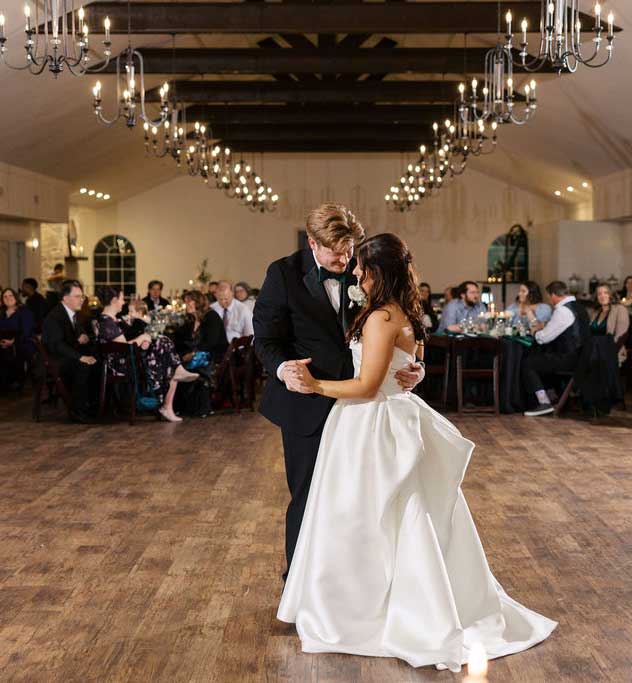 Bride and groom sharing their first dance inside the Willowood Ranch event center during a Texas wedding reception