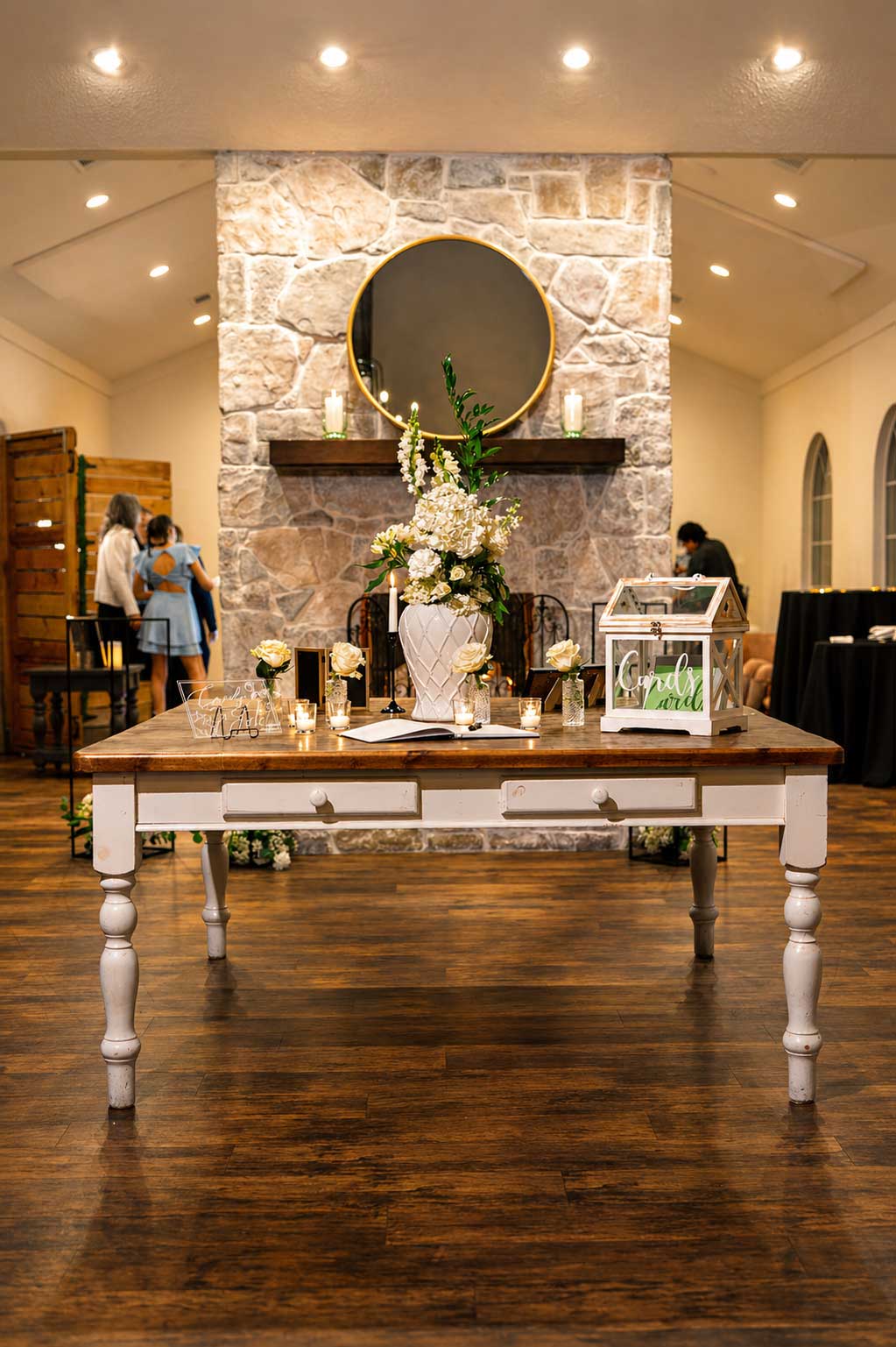 Wedding welcome table with floral arrangement and candles inside Willowood Ranch Event Center near Dallas, Texas