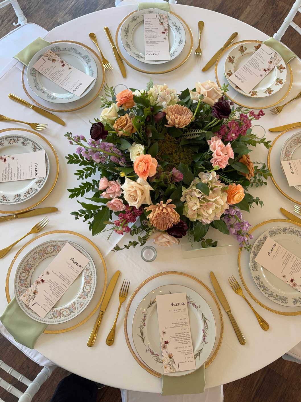 Round reception table with floral centerpiece, gold flatware, and soft pastel place settings at Willowood Ranch wedding venue