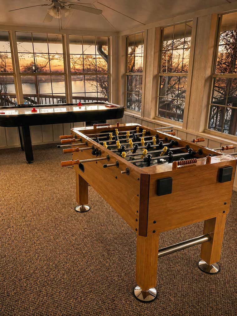 Game room at Willowood Ranch lodge with foosball table and shuffleboard by large windows