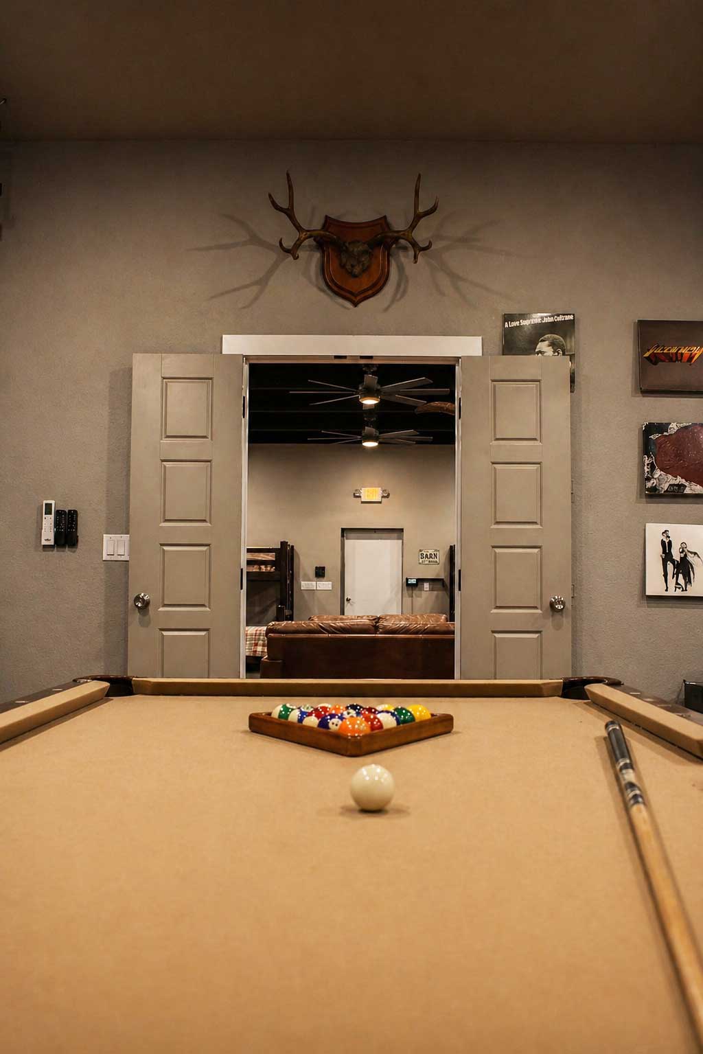 Pool table in Willowood Ranch lodge game room with lounge and bunk area beyond