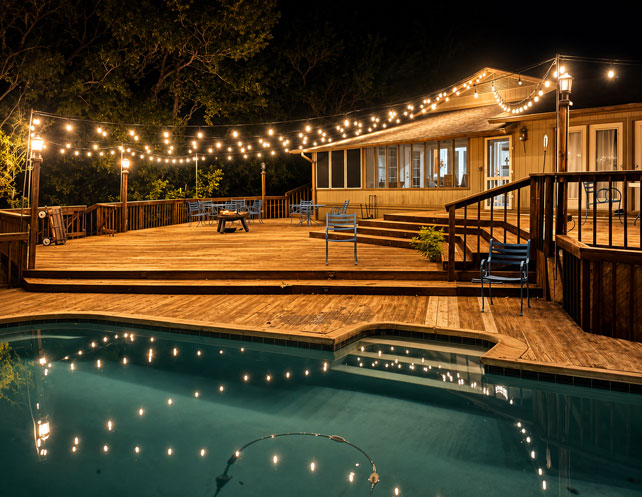Resort-style pool and expansive back deck with café string lights at Willowood Ranch event venue in Bells, Texas.