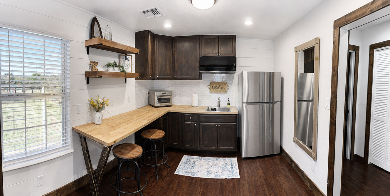 Private kitchenette inside The Longhorn studio cabin featuring refrigerator, sink, countertop seating, and modern appliances.